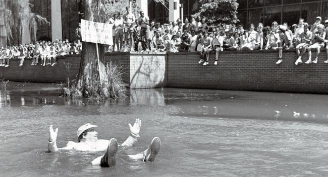 Phil Beridon jumps into Cypress Lake at Lagniappe Day in 1984 while a crowd of students cheers him on.