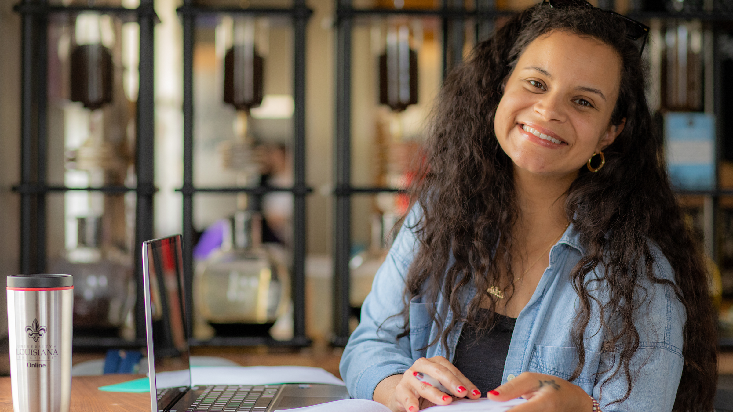 RN to BSN graduate Jaime Taylor smiles over her textbook and laptop.