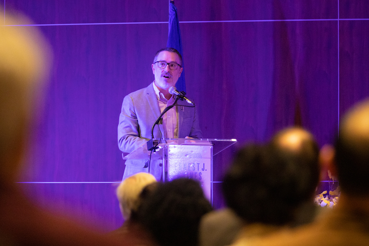 Wiley Cash speaks behind a lectern at Ernest Gaines stamp ceremony.