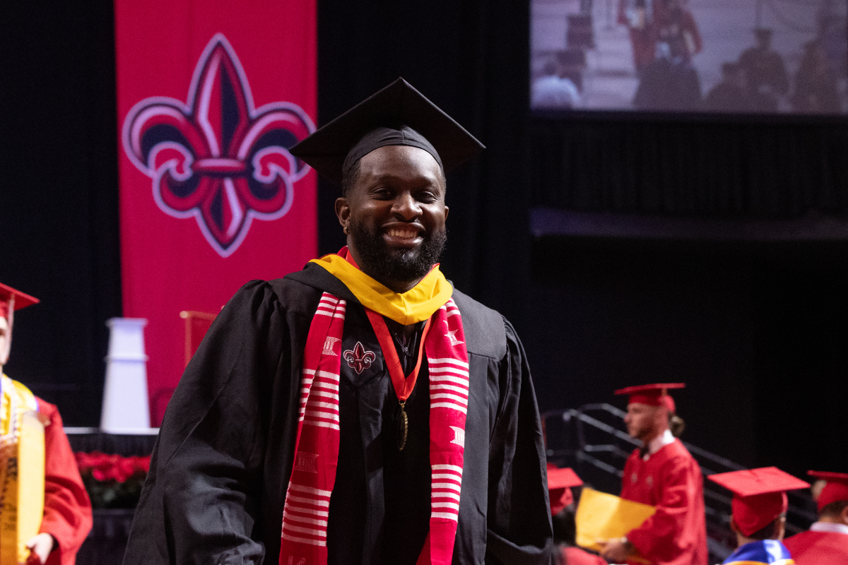 M.S. in Systems Tech graduate smiles in cap and gown after walking across the stage