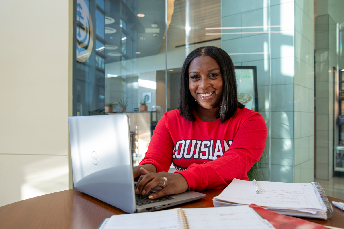 MSN graduate Shantell Dugas smiles for photo while studying in a red UL Lafayette t-shirt.