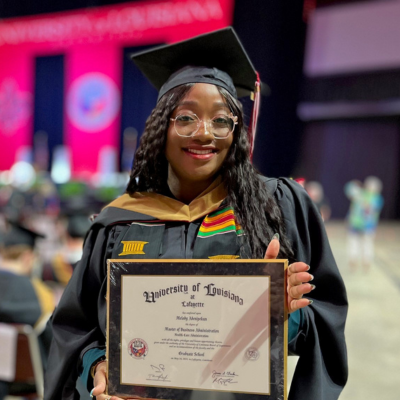 UL Lafayette MBA grad poses with degree after crossing the stage at commencement ceremony