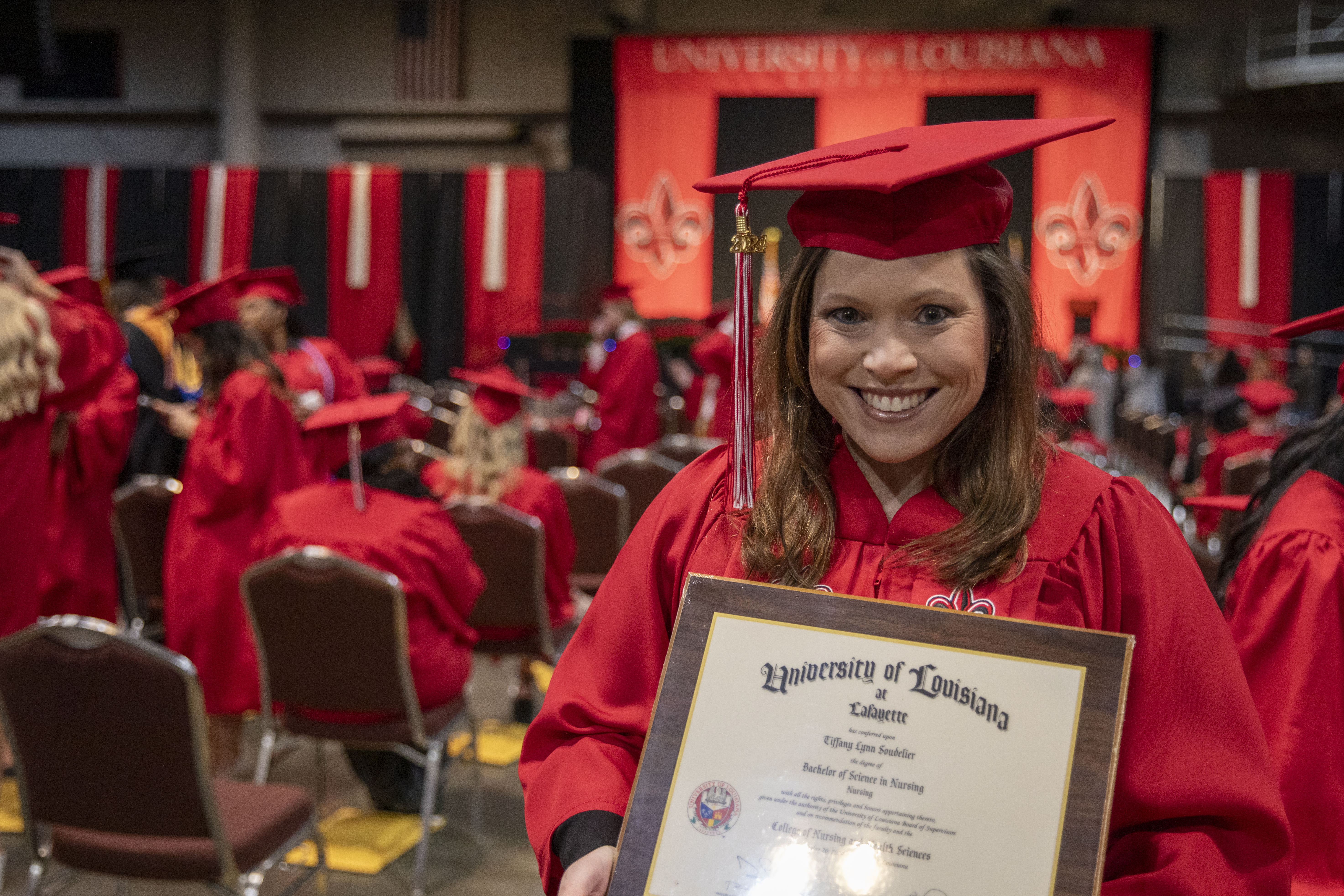 RN to BSN graduate Tiffany Soudelier smiles at Commencement while holding her new diploma.