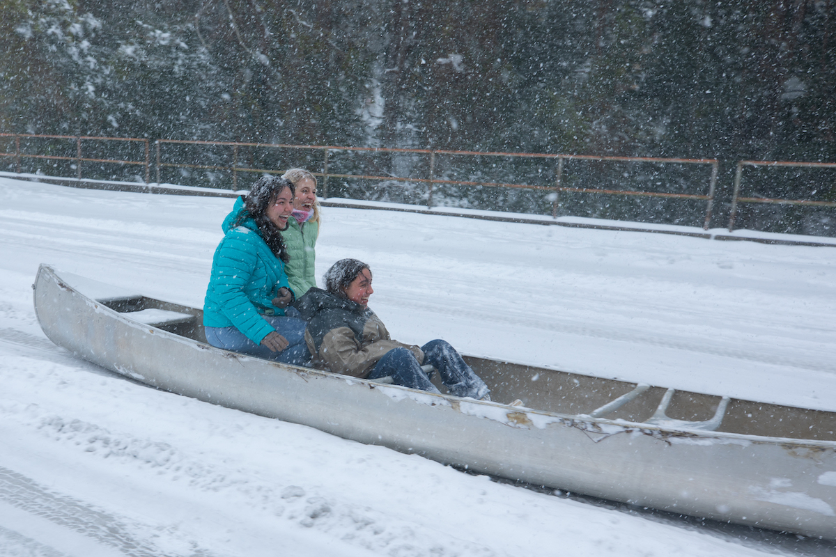 Students sled across the snow in a canoe during the blizzard of 2025.