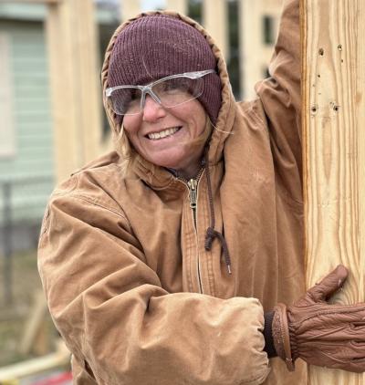 Bundled up in a jacket, leather gloves, and beanie, Lauren Lewis, 2023 graduate of the online general studies bachelor's program, leads a group of volunteers at a Habitat for Humanity build site.