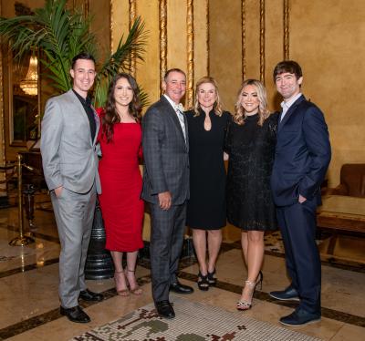 HPW student poses with her husband and children, all dressed in formal attire in a ballroom.