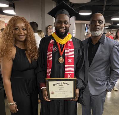 Systems Technology graduate Mike Evans smiles for photo holding his degree with his mother and father