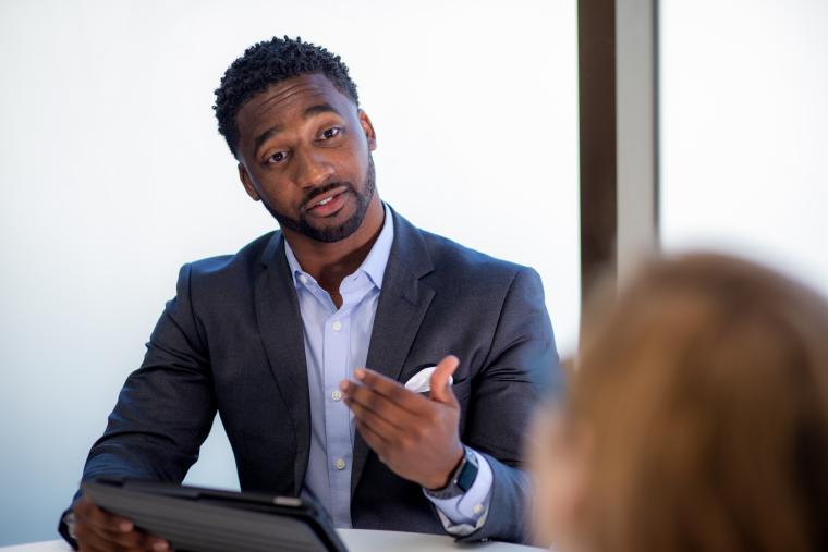 MBA grad presents in a conference room wearing formal work attire