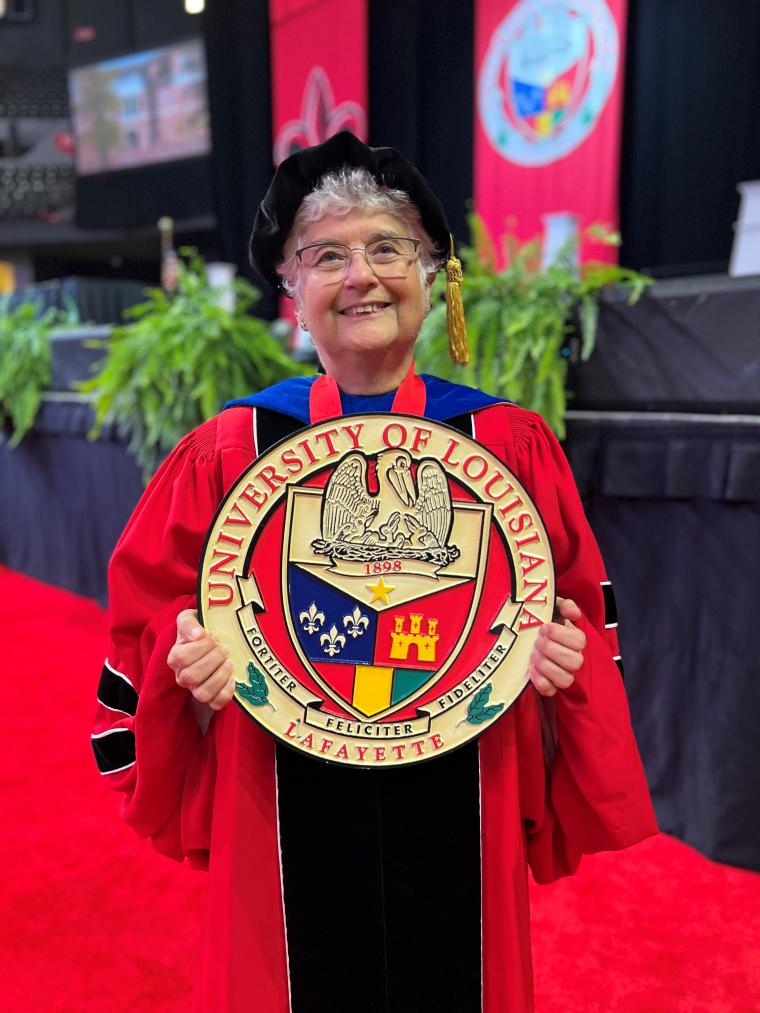 Susana Garcia holding the Grand Marshal seal in front of the graduation stage.