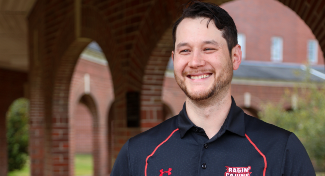 Jonathan Kim, CPA, is pictured on campus in a black, Ragin' Cajuns polo shirt. Kim earned both his bachelor's degree and master's degree at UL Lafayette.