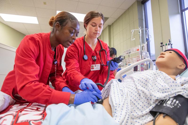 Two nursing students participate in a simulation lab.